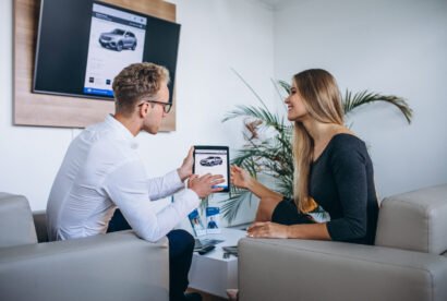 Man and woman in a car showroom using tablet