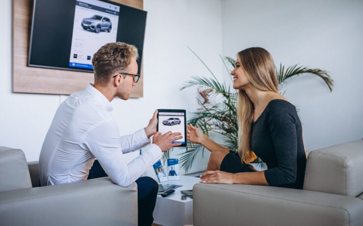 Man and woman in a car showroom using tablet