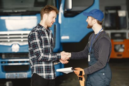 Two guys talking about work. Work in garage near truck. Transfer of documents with goods