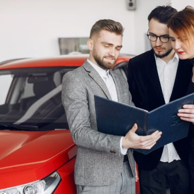 Couple in a car salon. Family buying the car. Elegant woman with her husband. Assistant with a clients